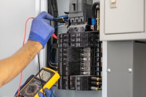 Electrician is using a digital meter to measure the voltage in an electrical panel